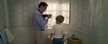Movie still from “Little Children” (2006), directed by Todd Field – A man and a boy in a bathroom; Medium shot, Over the shoulder angle