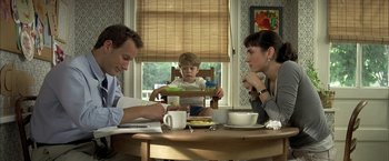 Movie still from “Little Children” (2006), directed by Todd Field – A man , woman , and a child sitting at a table; Medium shot, Over the shoulder angle