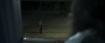 Movie still from “Little Children” (2006), directed by Todd Field – A man standing on the side of a road at night; Wide shot, Over the shoulder angle