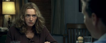 Movie still from “Little Children” (2006), directed by Todd Field – A woman sitting at a dining room table looking sad; Close Up shot, Over the shoulder angle