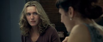 Movie still from “Little Children” (2006), directed by Todd Field – Two women sitting in front of each other in front of a wooden wall; Close Up shot, Over the shoulder angle
