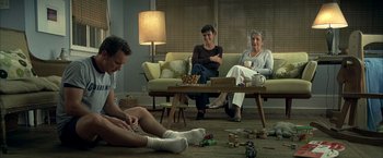 Movie still from “Little Children” (2006), directed by Todd Field – A group of people sitting on a couch in a living room; Wide shot, High angle