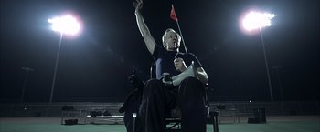 Movie still from “Little Children” (2006), directed by Todd Field – A man sitting in a chair holding a red flag; Medium shot, Low angle