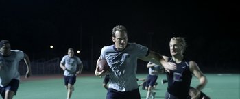 Movie still from “Little Children” (2006), directed by Todd Field – A group of men playing football on a field; Medium shot, Over the shoulder angle