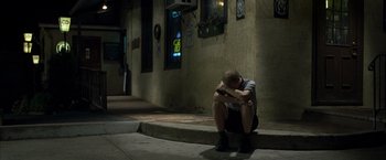 Movie still from “Little Children” (2006), directed by Todd Field – A man sitting on the curb of a street; Wide shot, High angle