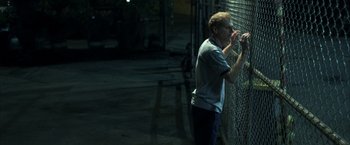 Movie still from “Little Children” (2006), directed by Todd Field – A man leaning against a fence looking at something on the ground; Medium shot, High angle