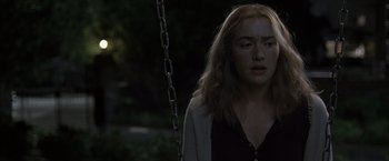 Movie still from “Little Children” (2006), directed by Todd Field – A woman sitting on top of a metal swing; Close Up shot, Over the shoulder angle