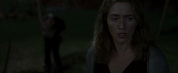 Movie still from “Little Children” (2006), directed by Todd Field – A woman with long brown hair standing in the dark; Close Up shot, Over the shoulder angle