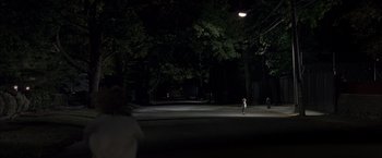 Movie still from “Little Children” (2006), directed by Todd Field – A person standing on the side of a road at night; Extreme Wide shot, High angle
