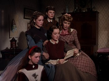 Movie still from “Little Women” (1949), directed by Mervyn LeRoy – A group of people sitting in a living room reading a book; Medium shot, High angle