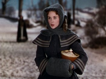 Movie still from “Little Women” (1949), directed by Mervyn LeRoy – A woman in a winter outfit holding a bowl of soup; Medium shot, Over the shoulder angle