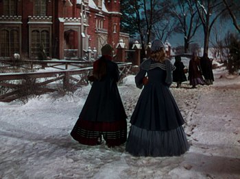 Movie still from “Little Women” (1949), directed by Mervyn LeRoy – Two women dressed in period clothing walk in the snow; Wide shot, High angle