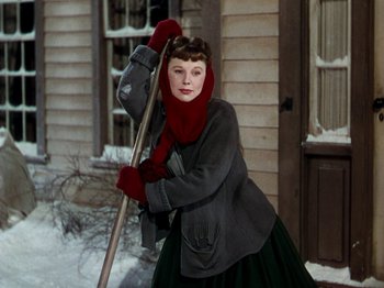 Movie still from “Little Women” (1949), directed by Mervyn LeRoy – A young woman holding a snow shovel in front of a house; Medium shot, Low angle