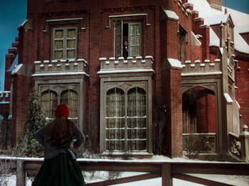 Movie still from “Little Women” (1949), directed by Mervyn LeRoy – A woman standing in front of a brick building; Extreme Wide shot, Low angle