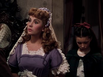 Movie still from “Little Women” (1949), directed by Mervyn LeRoy – A woman in a purple dress standing next to a girl; Medium shot, Over the shoulder angle