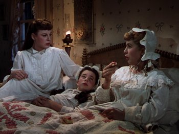 Movie still from “Little Women” (1949), directed by Mervyn LeRoy – A group of people sitting on a bed; Medium shot, High angle