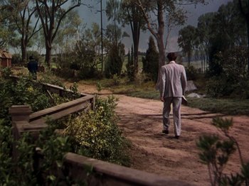 Movie still from “Little Women” (1949), directed by Mervyn LeRoy – A man walking down a dirt road holding an umbrella; Extreme Wide shot, High angle
