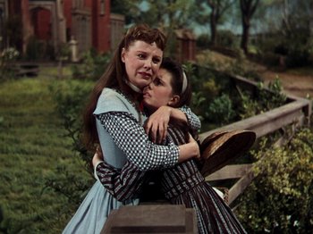 Movie still from “Little Women” (1949), directed by Mervyn LeRoy – Two women embracing each other while standing next to a fence; Medium shot, Low angle