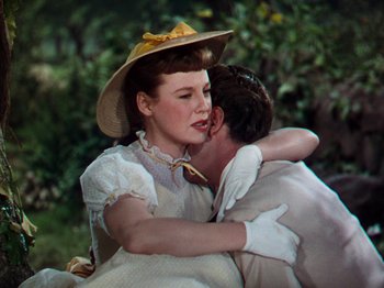 Movie still from “Little Women” (1949), directed by Mervyn LeRoy – A man and a woman embracing each other in front of a tree; Medium shot, High angle