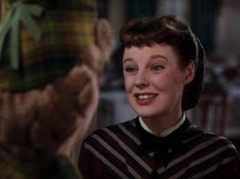 Movie still from “Little Women” (1949), directed by Mervyn LeRoy – A woman smiling at the camera while holding a teddy bear; Close Up shot, Over the shoulder angle