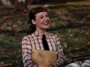 Movie still from “Little Women” (1949), directed by Mervyn LeRoy – A woman in a plaid shirt holding a brown paper bag; Medium shot, High angle