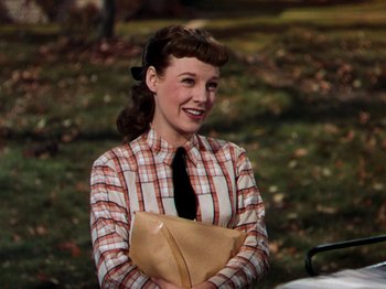 Movie still from “Little Women” (1949), directed by Mervyn LeRoy – A woman in a plaid shirt holding a brown paper bag; Medium shot, High angle