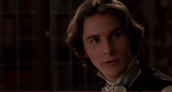 Movie still from “Little Women” (1994), directed by Gillian Armstrong – A man with long brown hair wearing a bow tie; Close Up shot, Over the shoulder angle