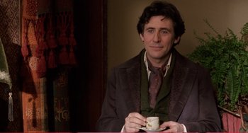 Movie still from “Little Women” (1994), directed by Gillian Armstrong – A man in a suit and tie holding a cup of coffee; Medium shot, Over the shoulder angle