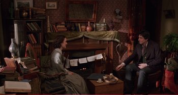 Movie still from “Little Women” (1994), directed by Gillian Armstrong – A woman sitting in front of a fireplace with a man; Wide shot, High angle