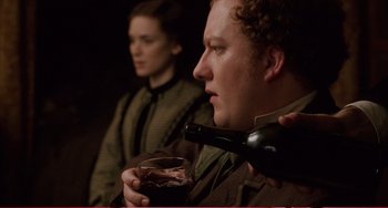 Movie still from “Little Women” (1994), directed by Gillian Armstrong – A man holding a glass of red wine while a woman watches; Close Up shot, Over the shoulder angle