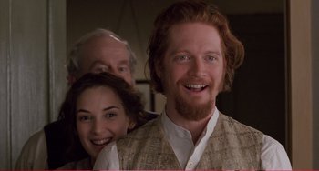 Movie still from “Little Women” (1994), directed by Gillian Armstrong – A man with a red beard is smiling for the camera with two other people; Close Up shot, Over the shoulder angle