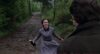 Movie still from “Little Women” (1994), directed by Gillian Armstrong – A woman in a grey dress is throwing a frisbee; Medium shot, Over the shoulder angle