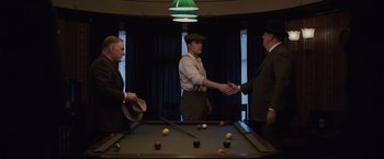 Movie still from “Live by Night” (2016), directed by Ben Affleck – A group of men shaking hands over a pool table; Medium shot, Over the shoulder angle