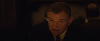 Movie still from “Live by Night” (2016), directed by Ben Affleck – An older man in a suit and tie looking at the camera; Close Up shot, Over the shoulder angle