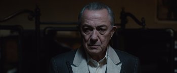 Movie still from “Live by Night” (2016), directed by Ben Affleck – An older man in a white shirt and a black jacket; Close Up shot, Low angle