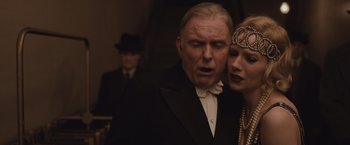 Movie still from “Live by Night” (2016), directed by Ben Affleck – An older man and a young woman in formal attire; Close Up shot, Low angle