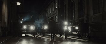 Movie still from “Live by Night” (2016), directed by Ben Affleck – A group of men walking down a street at night; Wide shot, Low angle