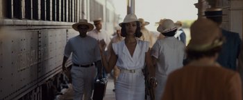 Movie still from “Live by Night” (2016), directed by Ben Affleck – A woman in a white dress and a hat; Medium shot, Over the shoulder angle