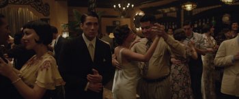 Movie still from “Live by Night” (2016), directed by Ben Affleck – A man and a woman dancing with a man in a suit and tie; Medium shot, Over the shoulder angle