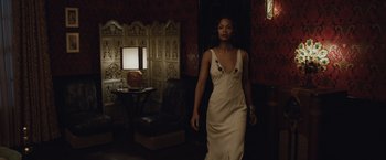 Movie still from “Live by Night” (2016), directed by Ben Affleck – A woman in a white dress standing in front of a chair; Medium shot, Low angle