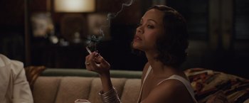 Movie still from “Live by Night” (2016), directed by Ben Affleck – A woman smoking a cigarette while sitting on a couch; Close Up shot, High angle