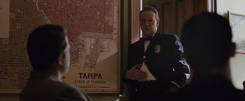 Movie still from “Live by Night” (2016), directed by Ben Affleck – A man standing in front of a map of tampa; Medium shot, Over the shoulder angle