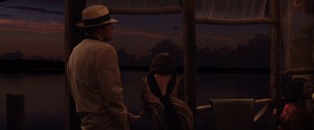 Movie still from “Live by Night” (2016), directed by Ben Affleck – A man and a woman standing next to each other near a body of water; Medium shot, High angle