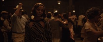 Movie still from “Live by Night” (2016), directed by Ben Affleck – A group of people standing around a room; Medium shot, Over the shoulder angle