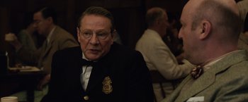 Movie still from “Live by Night” (2016), directed by Ben Affleck – An older man wearing a suit and tie; Close Up shot, Over the shoulder angle