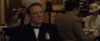 Movie still from “Live by Night” (2016), directed by Ben Affleck – A man in a suit and tie wearing a police badge; Close Up shot, Over the shoulder angle