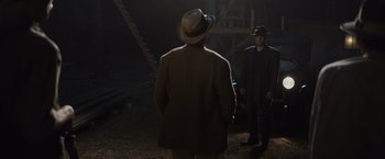 Movie still from “Live by Night” (2016), directed by Ben Affleck – A man in a hat and a suit standing next to another man in a suit; Wide shot, Over the shoulder angle
