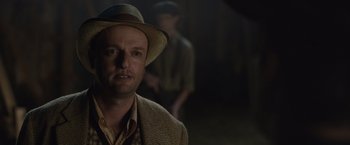 Movie still from “Live by Night” (2016), directed by Ben Affleck – A man wearing a hat in a dark room; Close Up shot, Over the shoulder angle