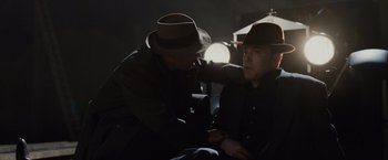 Movie still from “Live by Night” (2016), directed by Ben Affleck – A man in a hat and a man in a black jacket; Medium shot, Over the shoulder angle