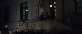 Movie still from “Live by Night” (2016), directed by Ben Affleck – Two men standing in front of a building at night; Extreme Wide shot, Low angle